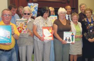 Reading in schools: Lions Club members with Lion Ben (back row, second right) holding some of the books collected.